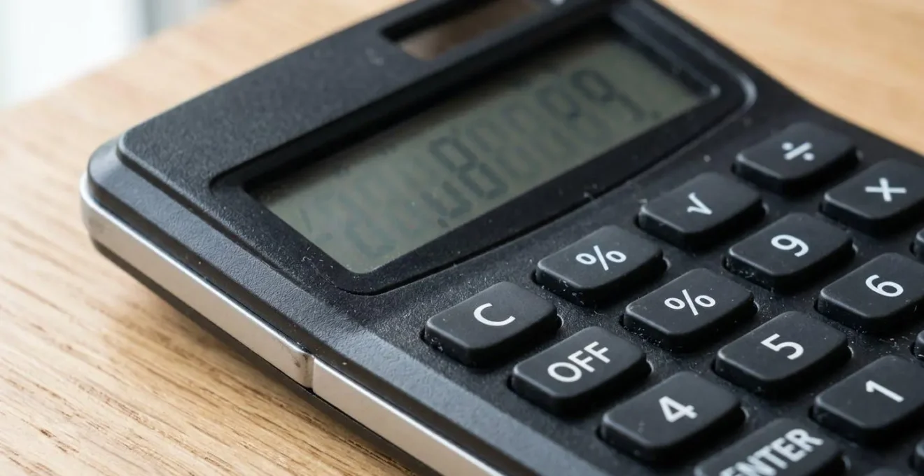 Gros plan sur une calculatrice financière moderne affichant un calcul de pourcentage, posée sur un bureau en bois clair contemporain